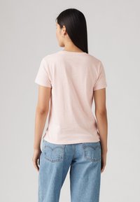 Rosa Baumwoll-T-Shirt mit kurzen Ärmeln, rundem Halsausschnitt und lässiger Passform, kombiniert mit hellblauen Jeans.
