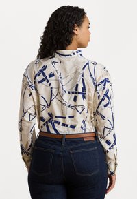 Blusa stampata in beige e blu navy, con un design geometrico e accenti blu. Maniche lunghe, polsini con bottoni e una vestibilità sagomata.