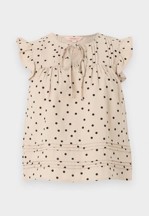 Μπεζ αμάνικο πουκάμισο με μαύρες πουά βούλες, βολάν στα κοντά μανίκια, μπροστινός δεσμός σε στρογγυλή λαιμόκοψη και οριζόντιες πτυχώσεις κοντά στο τελείωμα.