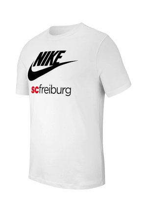 T-shirt bianca a maniche corte con logo Nike nero e testo rosso e nero "sc freiburg" sulla parte frontale, mostrata ad angolo su uno sfondo semplice.