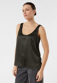 Schwarzes Satintanktop mit Rundhalsausschnitt und breiten Trägern, das eine lockere Passform und glatte Textur aufweist. Kombiniert mit grauer Hose.