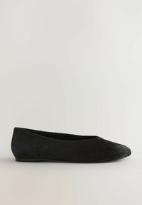 Chaussure de ballet plate noire avec un bout arrondi et une tige lisse texturée, présentée sur un fond neutre.