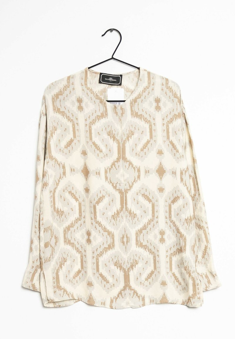 Blouse à manches longues en tissu léger, présentant un motif géométrique répétitif beige et crème, avec un col rond et des fentes sur les côtés.