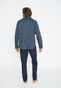 Chaqueta a rayas azul marino con cuello y mangas largas, combinada con pantalones lisos azul marino. La tela parece suave y duradera.