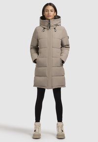 Cernă pură de iarnă, bej, cu guler înalt, închidere cu fermoar și șnururi ajustabile. Mâneci lungi și buzunare laterale completează designul.