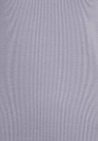 Top leve de canelado em lavanda claro. Material elástico com riscas verticais cria uma aparência texturizada. Sem padrões ou acentos visíveis.