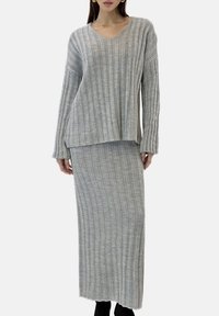 Gray ribbed knit two-piece outfit featuring a V-neck long-sleeve top and a matching ankle-length skirt with raw edges.