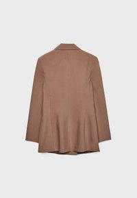 Veste marron sur mesure à manches longues, avec coutures apparentes au dos et ourlet légèrement évasé, présentée sur un fond blanc uni.