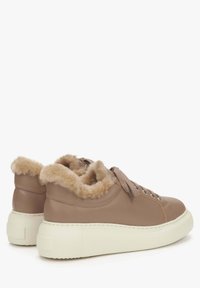 Bruine leren sneakers met een nepbont kraag, ronde neus en dikke witte rubbere zool. Voorzien van platte veters en zilveren oogjes.