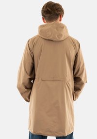 Veste imperméable beige avec capuche, présentant une coupe décontractée, des manches longues et une taille ajustable. Texture lisse, design minimaliste.