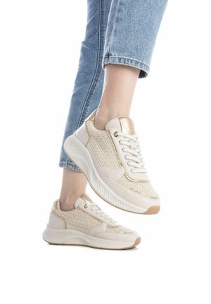 Zapatillas beige con punto texturizado y paneles de cuero suave, puntera redonda, diseño con cordones y suela acolchada. Acabados dorados en los tacones.