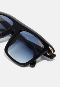 Ochelari de soare mătuți, de dimensiuni mari, cu lentile degradate albastre, având o formă rectangulară îndrăzneață și accente aurii pe balamale. Design texturat al brațelor.