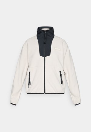 Veste en polaire beige clair avec des panneaux noirs, fermeture éclair sur le devant, col haut, poches latérales zippées et logo Columbia sur la poitrine.