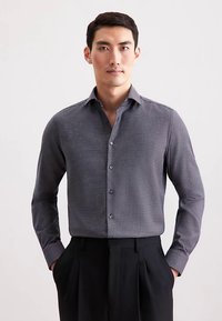 Camicia da uomo con bottoni di colore grigio scuro con un piccolo motivo a quadretti. Presenta maniche lunghe e un colletto classico. Tessuto liscio e strutturato.