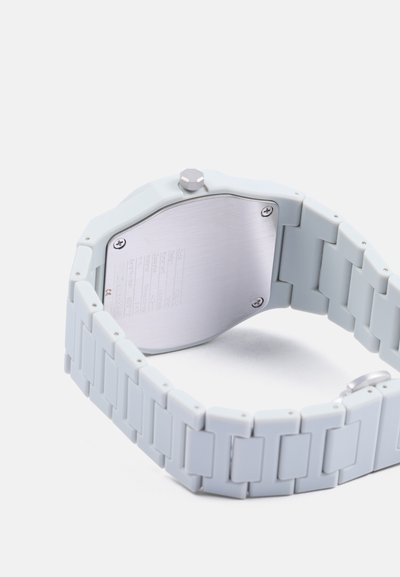 Montre intelligente gris clair avec un bracelet en silicone et un dos en acier inoxydable. Caractéristiques : couronne hexagonale, texture lisse et maillons à motif.