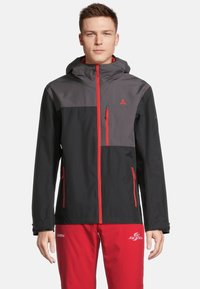 Schwarze und graue wasserdichte Jacke mit Kapuze, ausgestattet mit roten Reißverschlüssen und Akzenten, Reißverschlusstaschen und einem modernen, figurschmeichelnden Design.