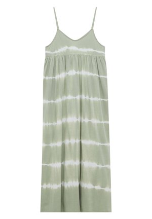 Femme portant une robe midi tie-dye verte et blanche sans manches avec de fines bretelles et des sandales compensées beiges sur fond blanc.