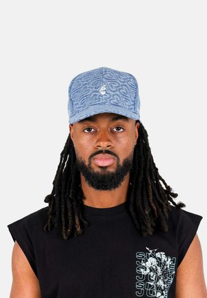 Denim cap with light blue color, embroidered logo on front, curved brim, and textured pattern. Black sleeveless shirt underneath.