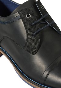 Zwarte leren schoen met een gestructureerde zwarte stoffen accent, blauwe stiksels en metalen veterogen. Heeft een gladde afwerking en een ronde neus.