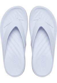 Chanclas blancas de Crocs con plantillas contorneadas y correas anchas, con la marca "crocs" en relieve en la plantilla y las correas.