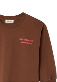 Brown long-sleeve T-shirt made of cotton with a crew neckline. Features a pink "AMERICAN VINTAGE" graphic on the left chest area.