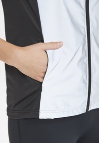Zwart-witte ritsjack met een zijzak, zachte stof, slim fit, met contrasterende kleuren en strakke naadlijnen.