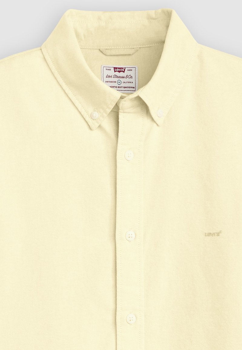 Levi's Button-down-Hemd in Cremefarbe mit klassischem Kragen, weißen Knöpfen und dezentem Levi's-Logo auf der Brust und einem Etikett innen am Kragen.