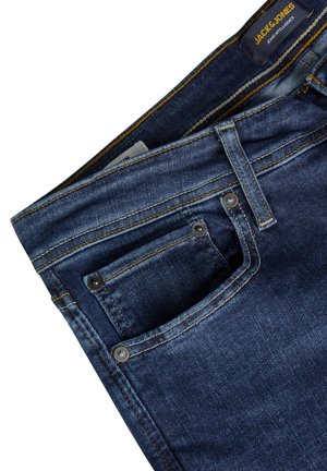 Jean en denim bleu foncé avec une coupe droite, présentant des coutures jaunes contrastantes, une petite poche et des accents de boutons en métal.