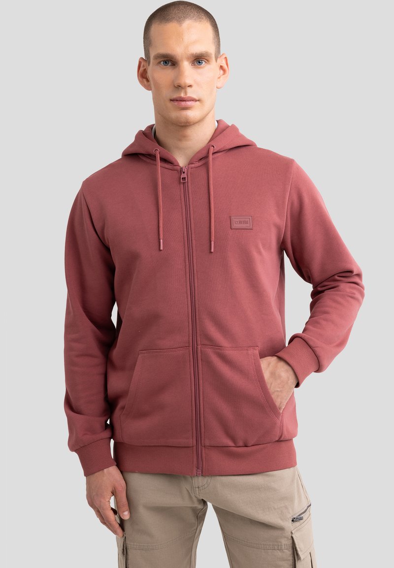 Kapuzensweatshirt zum Zuziehen in staubigem Rose, mit einem Logo-Patch auf der Vorderseite, seitlichen Taschen und gerippten Bündchen, aus einem weichen Baumwollmischgewebe gefertigt.