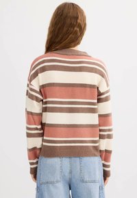 Suéter de rayas en tela suave, con bandas alternas de rosa, crema y marrón, cuello redondo y puños acanalados.