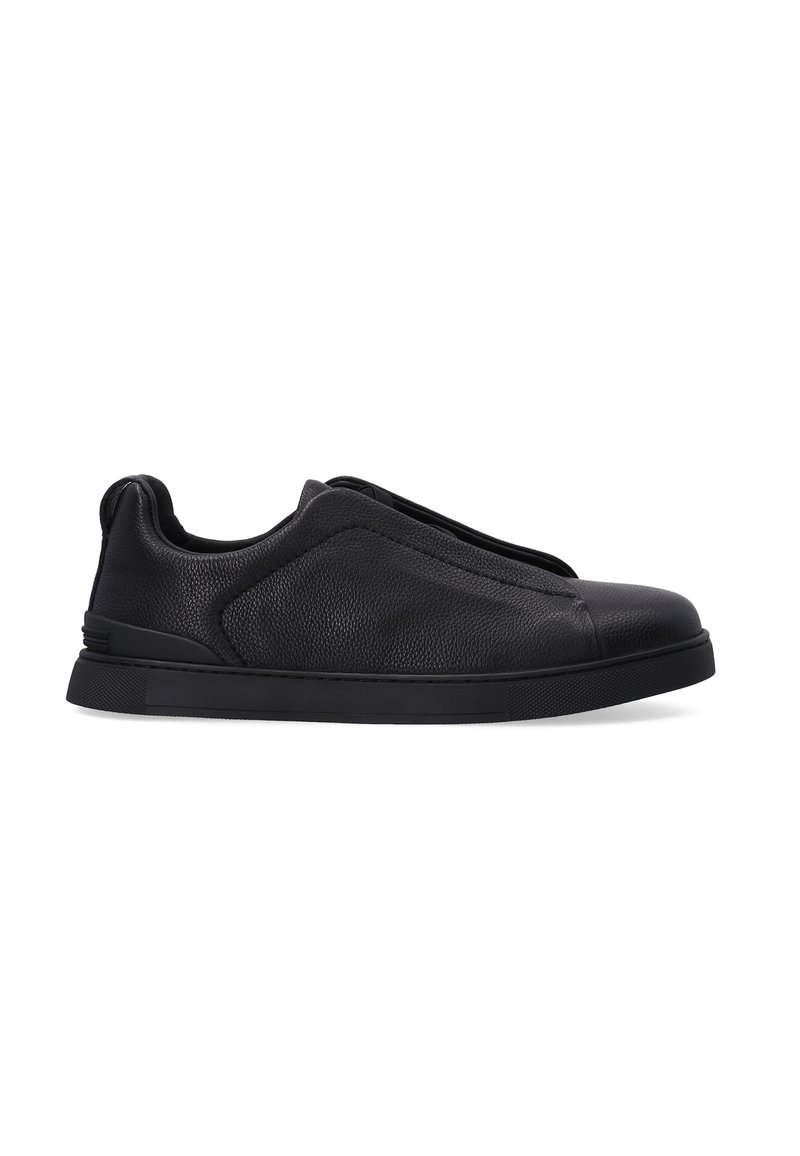 Černé kožené slip-on boty s texturovaným povrchem, zaoblenou špičkou a silnou černou gumovou podrážkou. Minimalistický design bez šněrování.