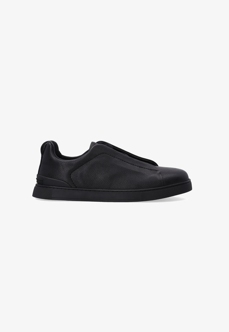 Černé kožené slip-on boty s texturovaným povrchem, zaoblenou špičkou a silnou černou gumovou podrážkou. Minimalistický design bez šněrování.