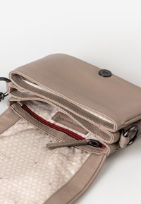 Piccola borsa a tracolla in pelle taupe con pattina, chiusura a scatto magnetico e fodera interna a fantasia con tasca con zip rossa.