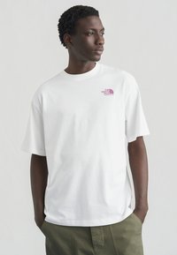 Λευκό βαμβακερό t-shirt με κοντά μανίκια, που διαθέτει μικρό μοβ λογότυπο North Face στο στήθος και άνετη εφαρμογή.