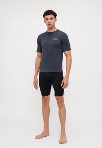 Completo sportivo da uomo composto da una maglietta a maniche corte in blu navy con logo "LE COL" e pantaloni corti compressivi neri, realizzati in tessuto elastico.