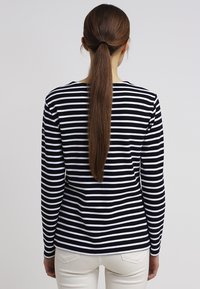 Langærmet stribet t-shirt i sort og hvid, med rund halsudskæring og lige søm. Stoffet har en blød tekstur.