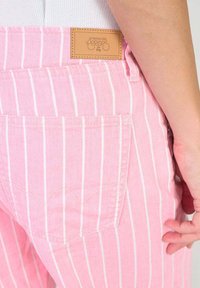Roze gestreepte denim broek met een leren label op de tailleband. Opvallende stiksels op de achterzak vormen een hartvorm. Gladde textuur.