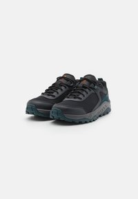 Czarne buty sportowe z teksturowaną siateczką, wzmocnionym czubkiem i tealową gumową podeszwą. Posiadają sznurowany design i pomarańczowe akcenty.