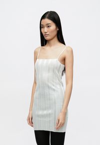 Pletené šaty svetlo šedej farby s tenkými vertikálnymi pruhmi, s rovný strihom, tenkými ramienkami a hladkou textúrou.