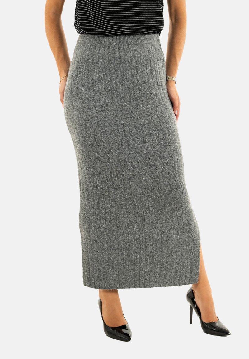 Falda de punto acanalado gris con cintura alta y abertura lateral, combinada con tacones altos de charol negros. Textura suave y silueta ajustada.