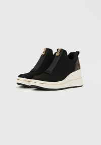 Sneakers alte nere in tessuto mesh, con chiusura a zip, dettagli dorati e suola a zeppa bianca texturizzata.