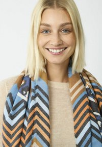 Écharpe multicolore avec un motif en chevrons bleu, marron et orange, fabriquée en tissu doux, drapée autour du cou.
