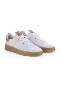 Des baskets en cuir blanc présentent un accent en suède tan au niveau du talon, des lacets ronds et une semelle en caoutchouc avec un motif texturé.