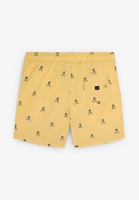 Pantaloni de baie galbeni cu un model repetat de craniu și oase încrucișate negre. Talie elastică cu un buzunar la spate și un accent pătrat negru.