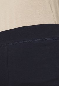 Beige och marinblått färgblockerat текстil med en mjuk yta, med en kontrasterande sömlinje. Tyget är lätt och flexibelt.