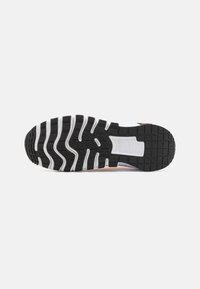 Semelle en caoutchouc noir et blanc d’une chaussure de course, montrant le motif de la bande de roulement et les détails du design sur un fond uni.