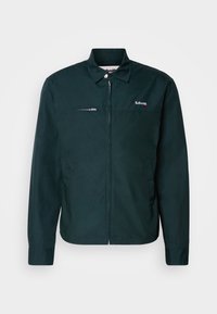 Donkergroene jas met een ritsluiting, lange mouwen, knoopkraag, borstzak met rits en geborduurd logo aan de linkerzijde.