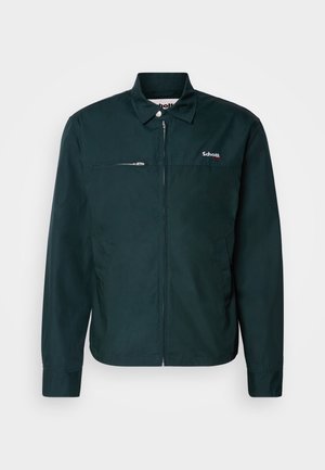 Veste vert foncé avec une fermeture éclaire, manches longues, col boutonné, poche poitrine avec fermeture éclair et logo brodé sur le côté gauche.