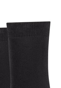 Calzini neri con una texture liscia e polsini a coste. Il design presenta un colore uniforme senza motivi o dettagli hardware.