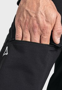 Schwarze Sporthose mit einer Reißverschlusstasche am rechten Oberschenkel. Aus glattem, strukturiertem Stoff und mit einem kleinen weißen Logo-Akzent.